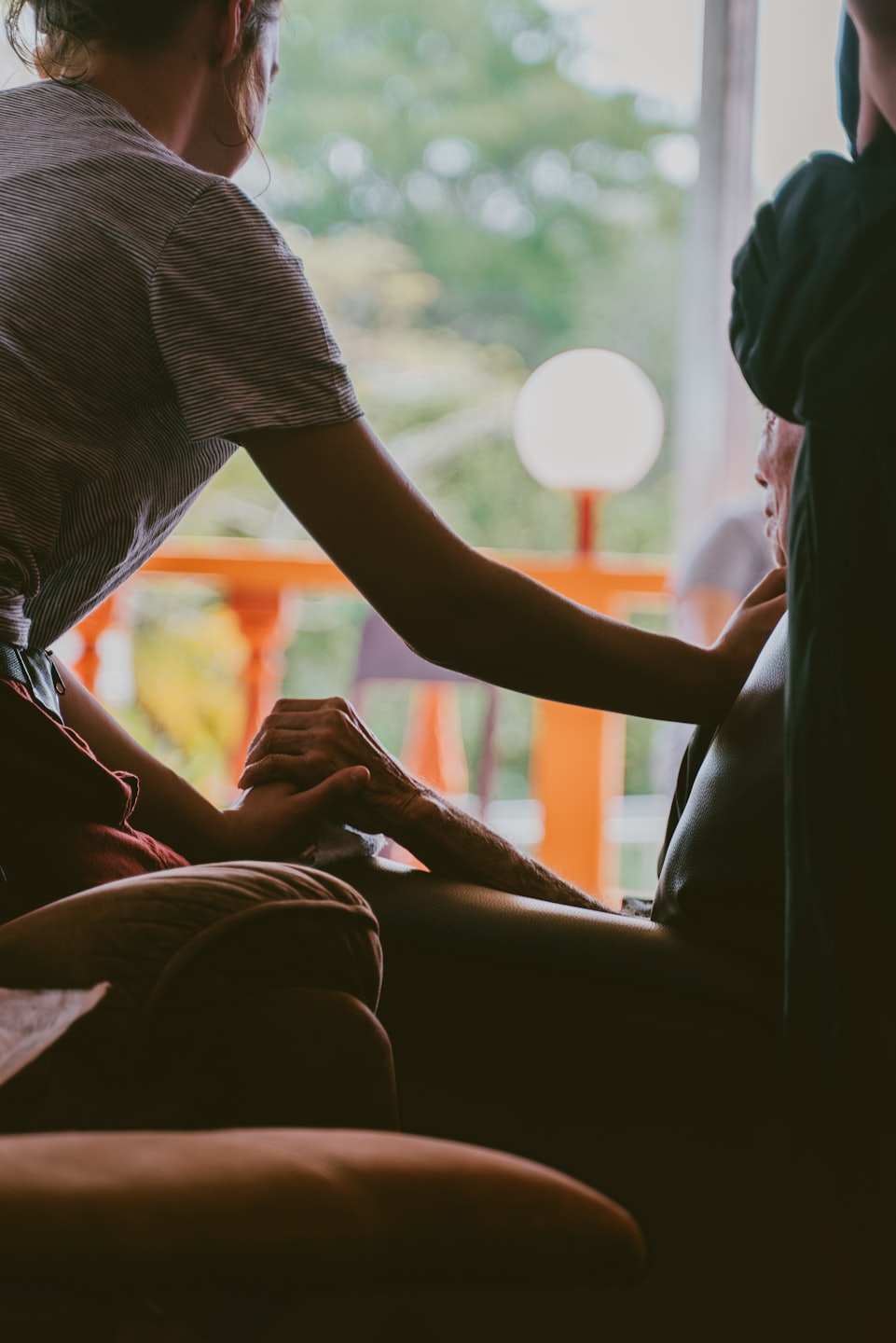 Two people holding hands and touching shoulders indoors.